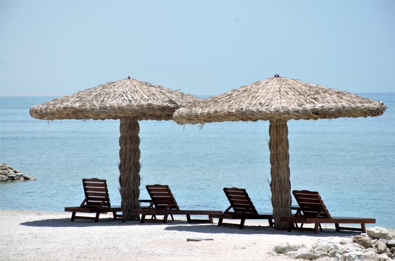 כסאות נוח תחת שמשיות בחוף בבחריין